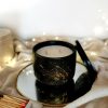 Artisanal scented candle in a black container with gold motifs